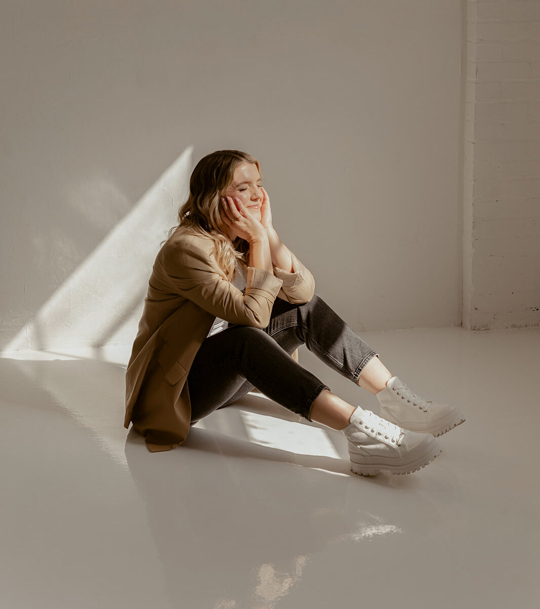 Pre-Launch Marketing Strategy Featured Image | Reveal Studio Kaili in a Tan Jacket sitting on the floor in a shadow