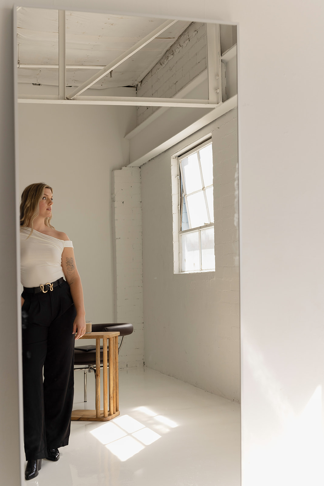 conversion copywriter kaili standing in front of a mirror wearing a white top and black slacks